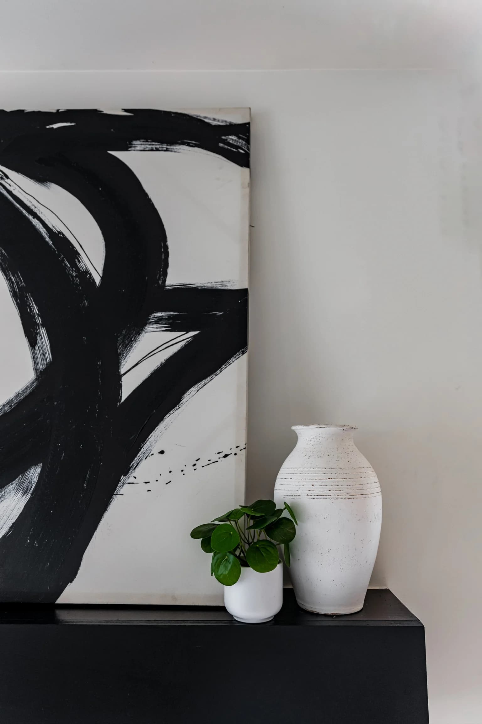 Black and white abstract canvas with a white vase and small plant