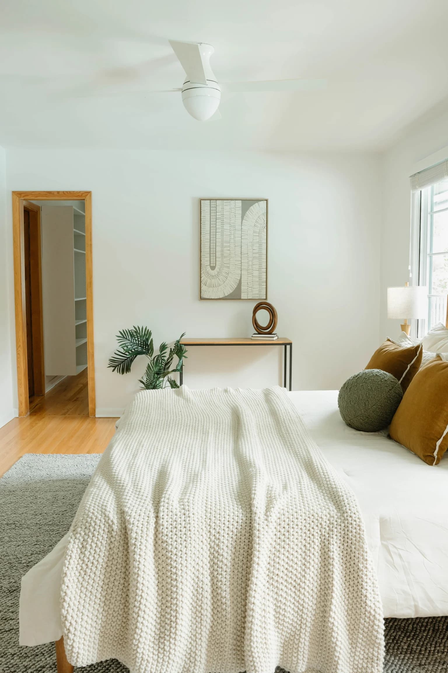 Bed with a chunky cream knit throw and mustard pillows