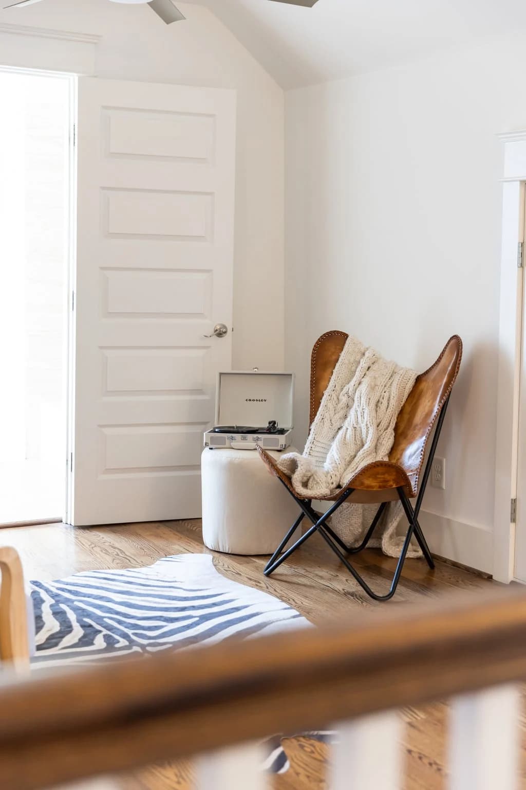 Bedroom reading corner with a leather butterfly chair and a zebra print rug