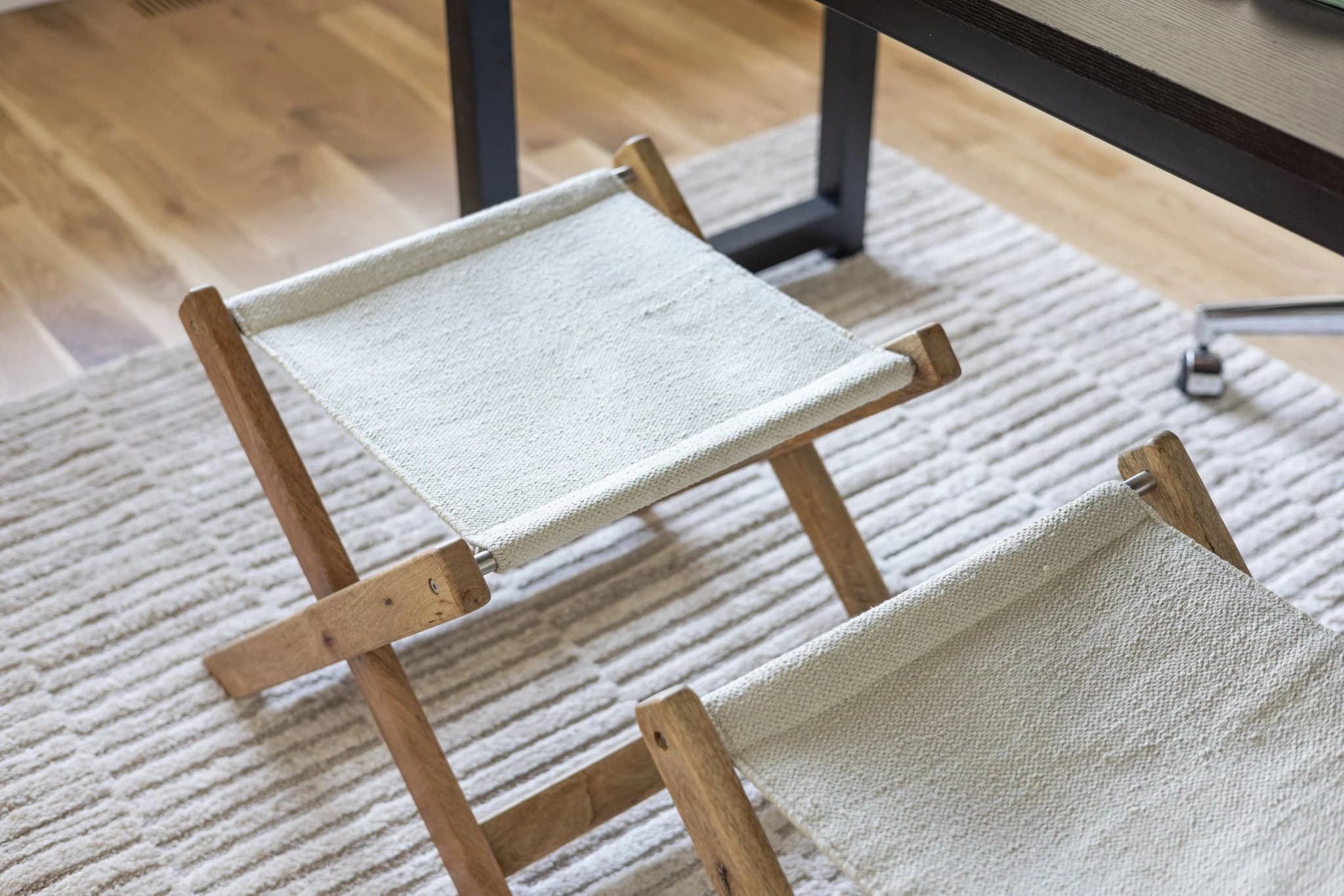 Wood and canvas folding bench on a textured cream rug