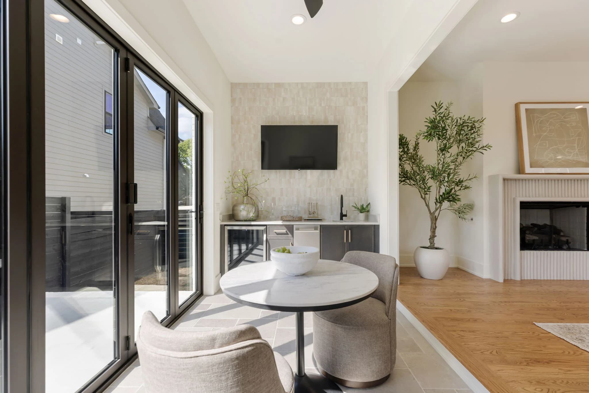 Breakfast nook with a round marble table and boucle chairs beside sliding glass doors and a tiled wet bar