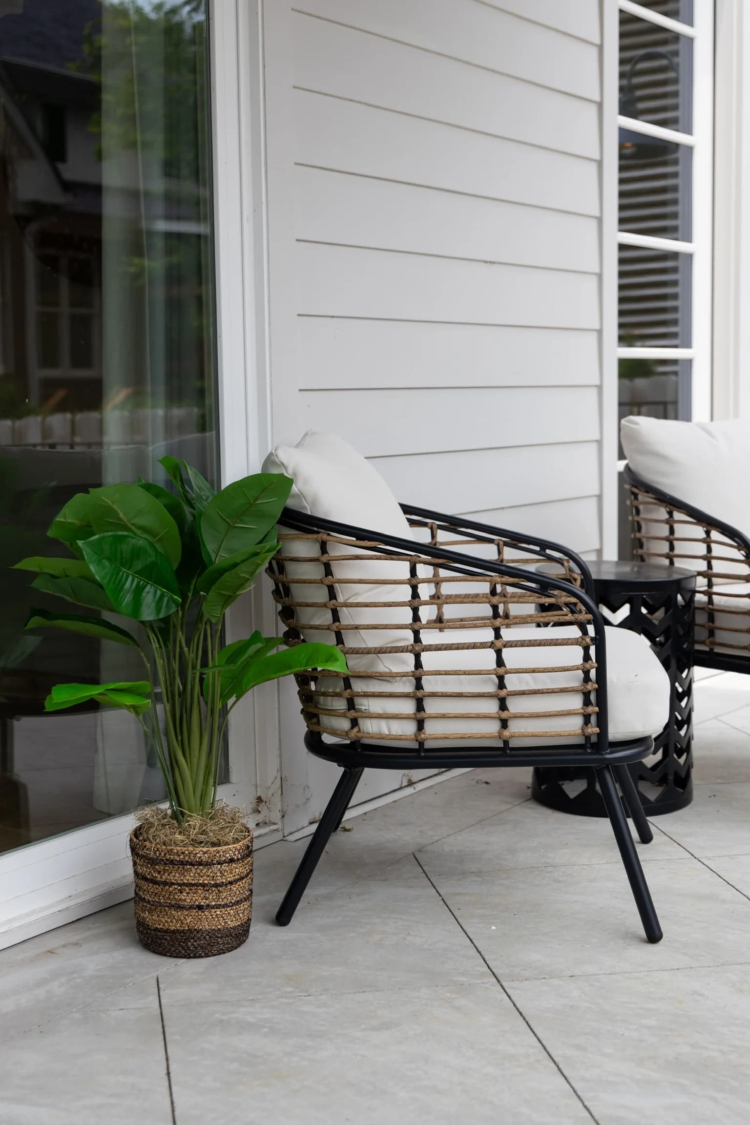 Covered porch with a woven rattan chair and a potted plant