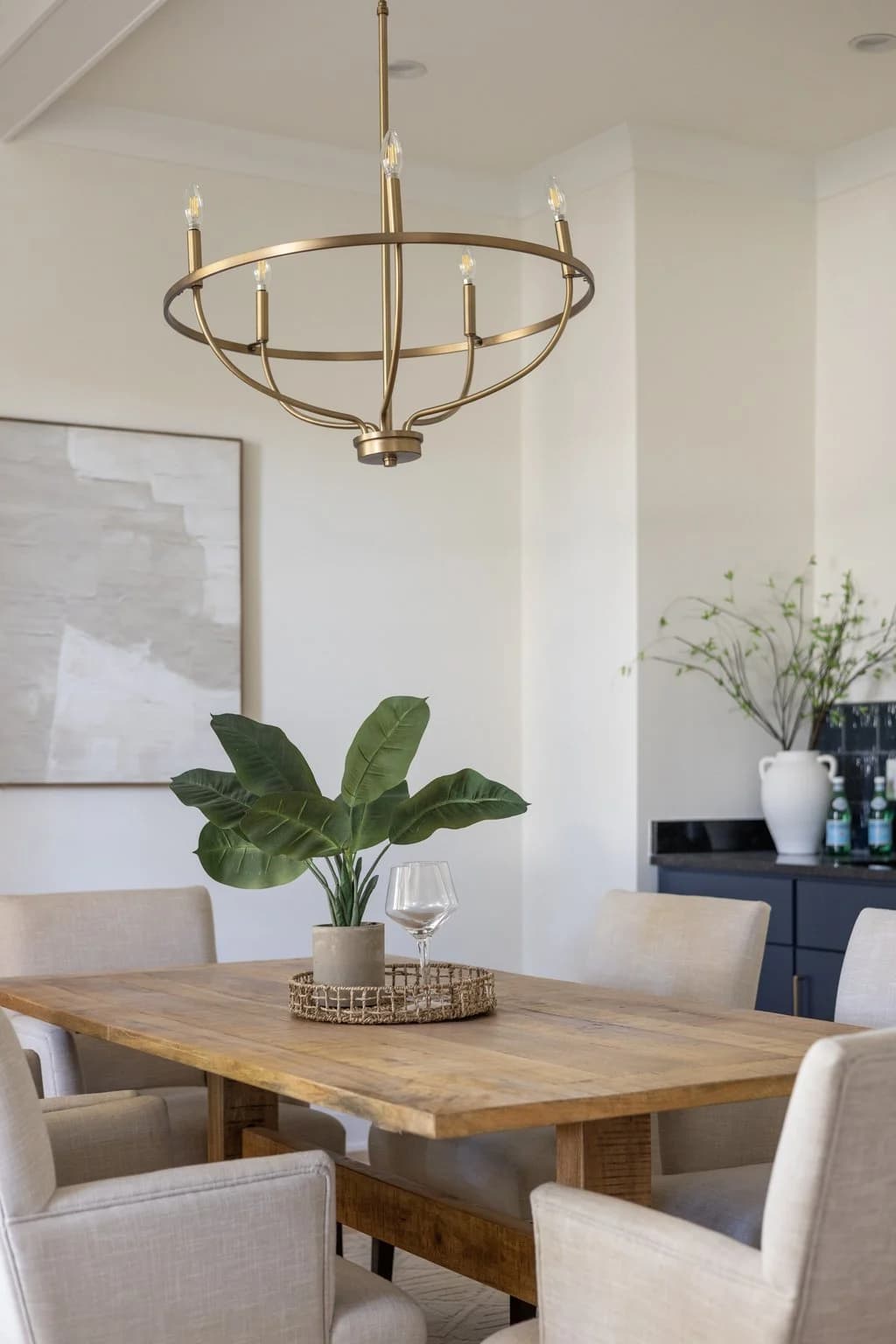 Dining room with a reclaimed wood table, cream upholstered chairs, and a brass ring chandelier