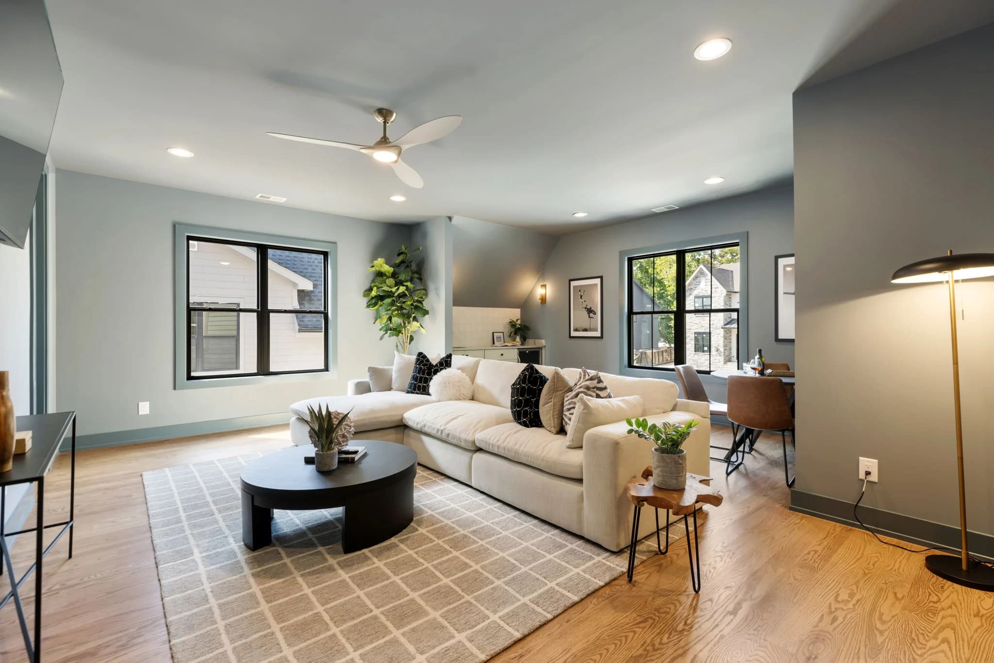 Family room with sage walls, a cream sectional, a round black coffee table, and a brass floor lamp