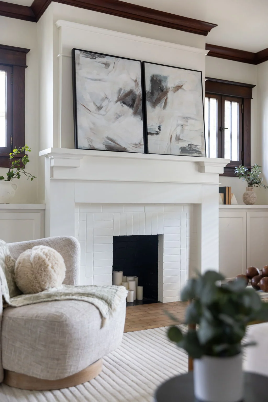Boucle swivel chair beside a white painted fireplace with an abstract diptych above