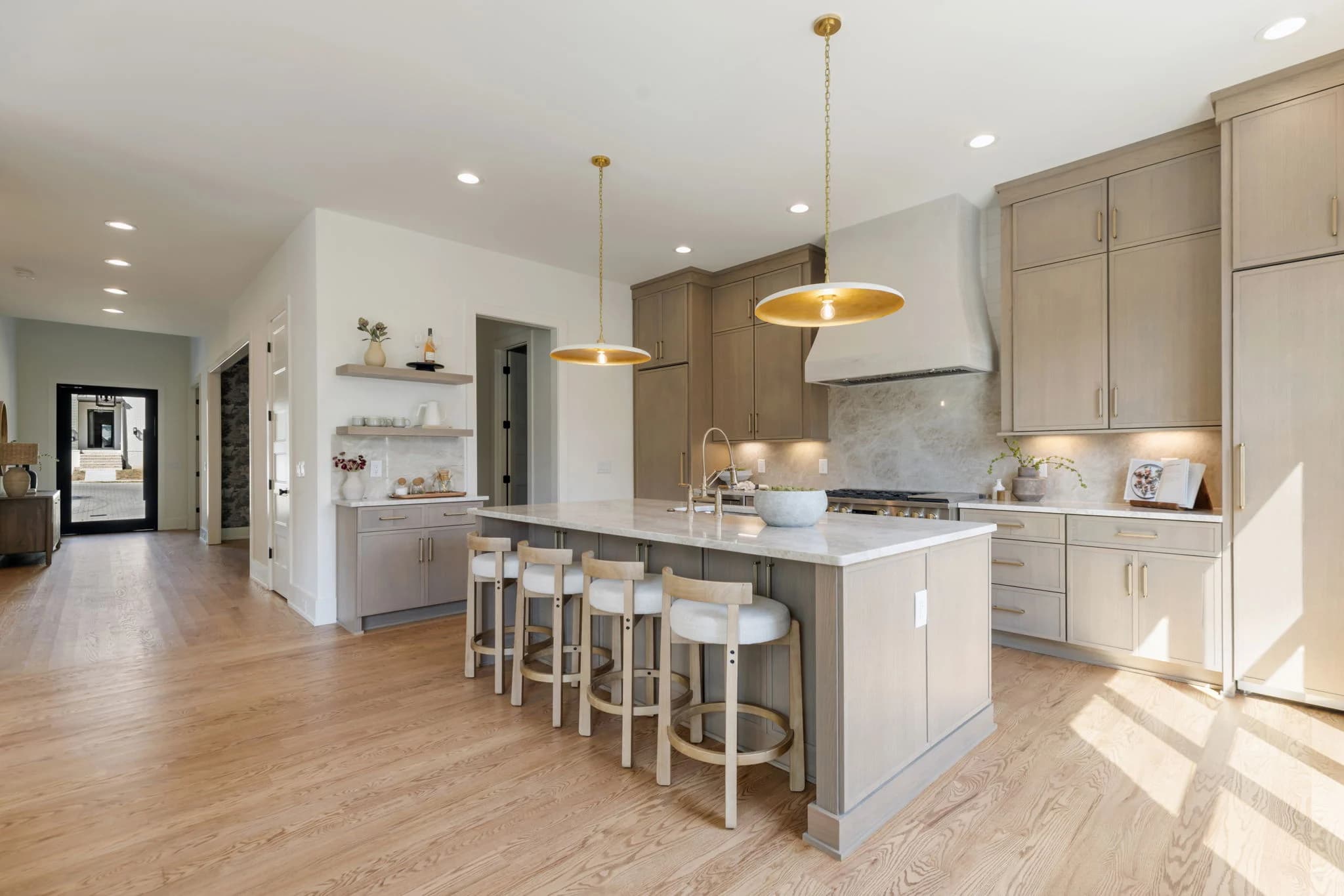 Open kitchen with a brass pendant over the island and a hallway leading to a glass front door