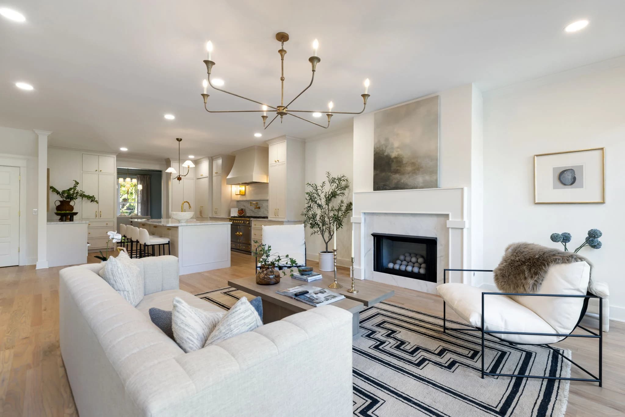Cream sofa and a sling chair around a woven coffee table, open to a white kitchen beyond