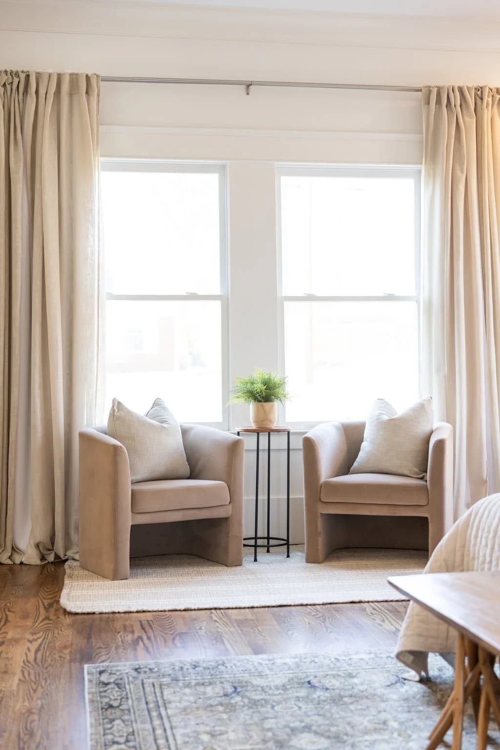 Window sitting area with two upholstered chairs and floor length linen drapes