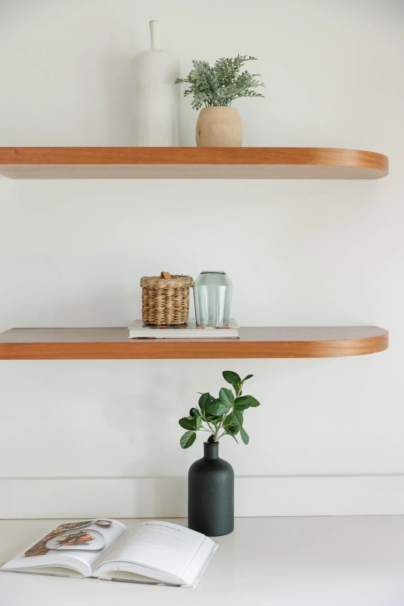 Floating wood shelves styled with ceramics, a basket, and greenery